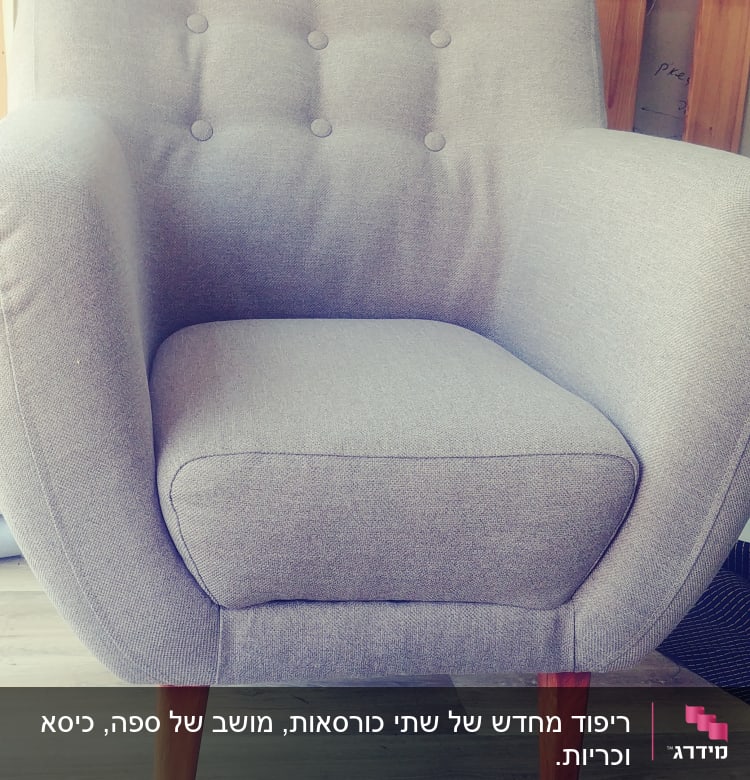 כורסה מרופדת עם רגלי עץ על רקע סלילי חוטים צבעוניים